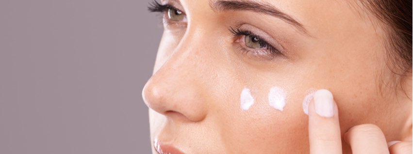 A woman applying moisturiser to her face