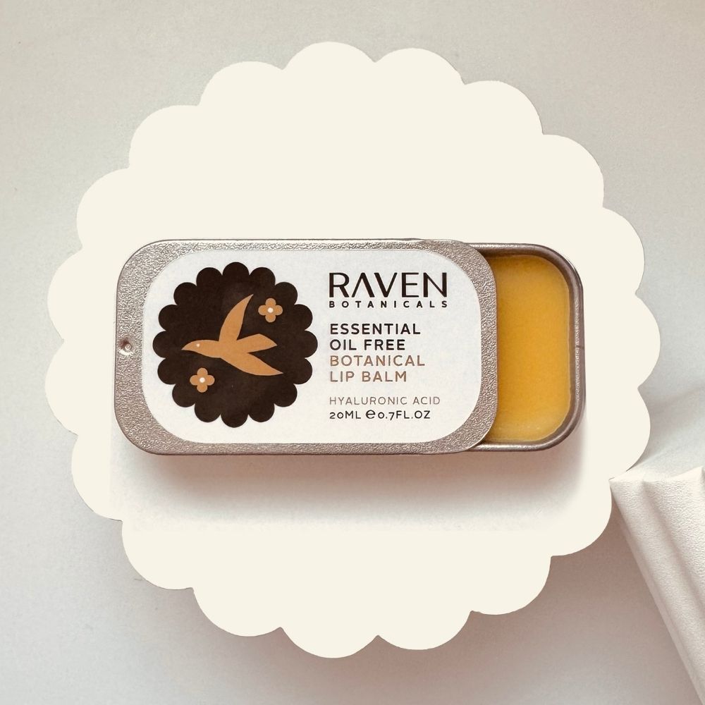 Essential Oil Free natural Lip Balm by Scottish Skincare brand Raven Botanicals, displayed open on a white riser in a plastic free sliding lid tin