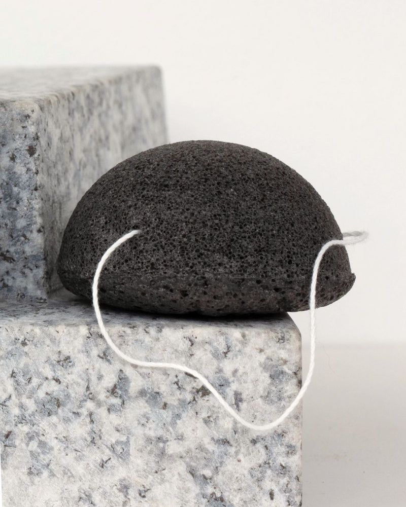 Natural charcoal konjac sponge sitting on a granite surface