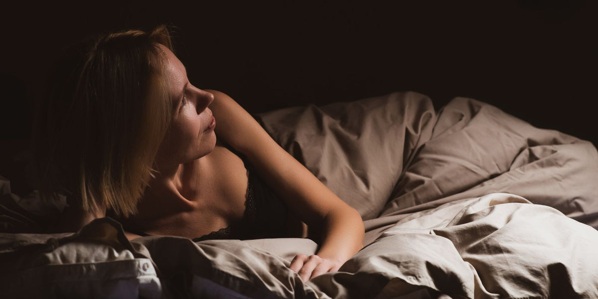 A woman waking up in a comfortable looking bed in a dark room