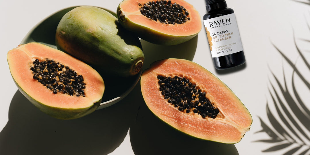image of cut open papaya with a bottle of 24k raven botanicals cleanser