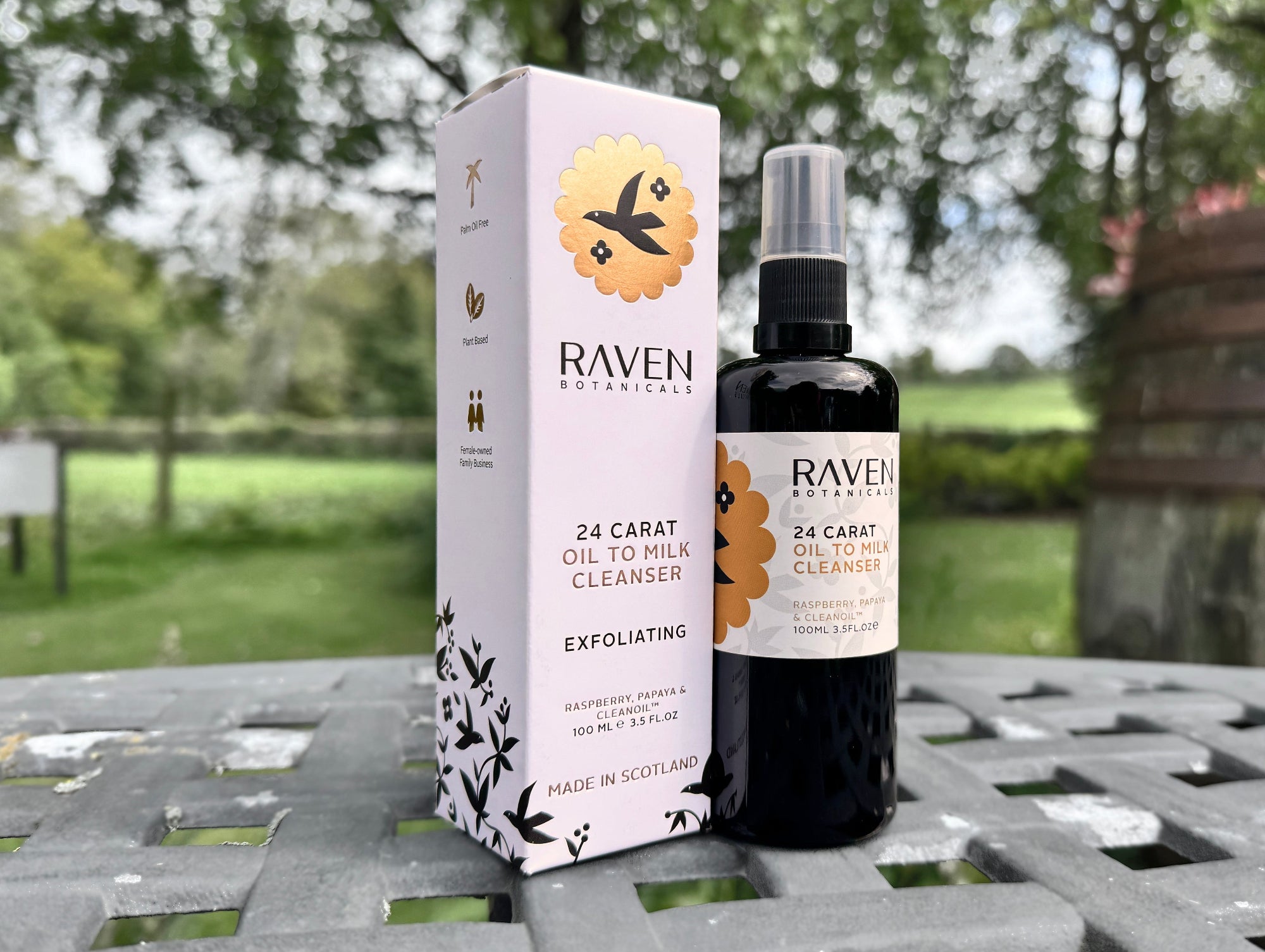 Raven Naturals 24 Carat Oil to Milk Cleanser bottle and packaging on a metal surface with a natural background.