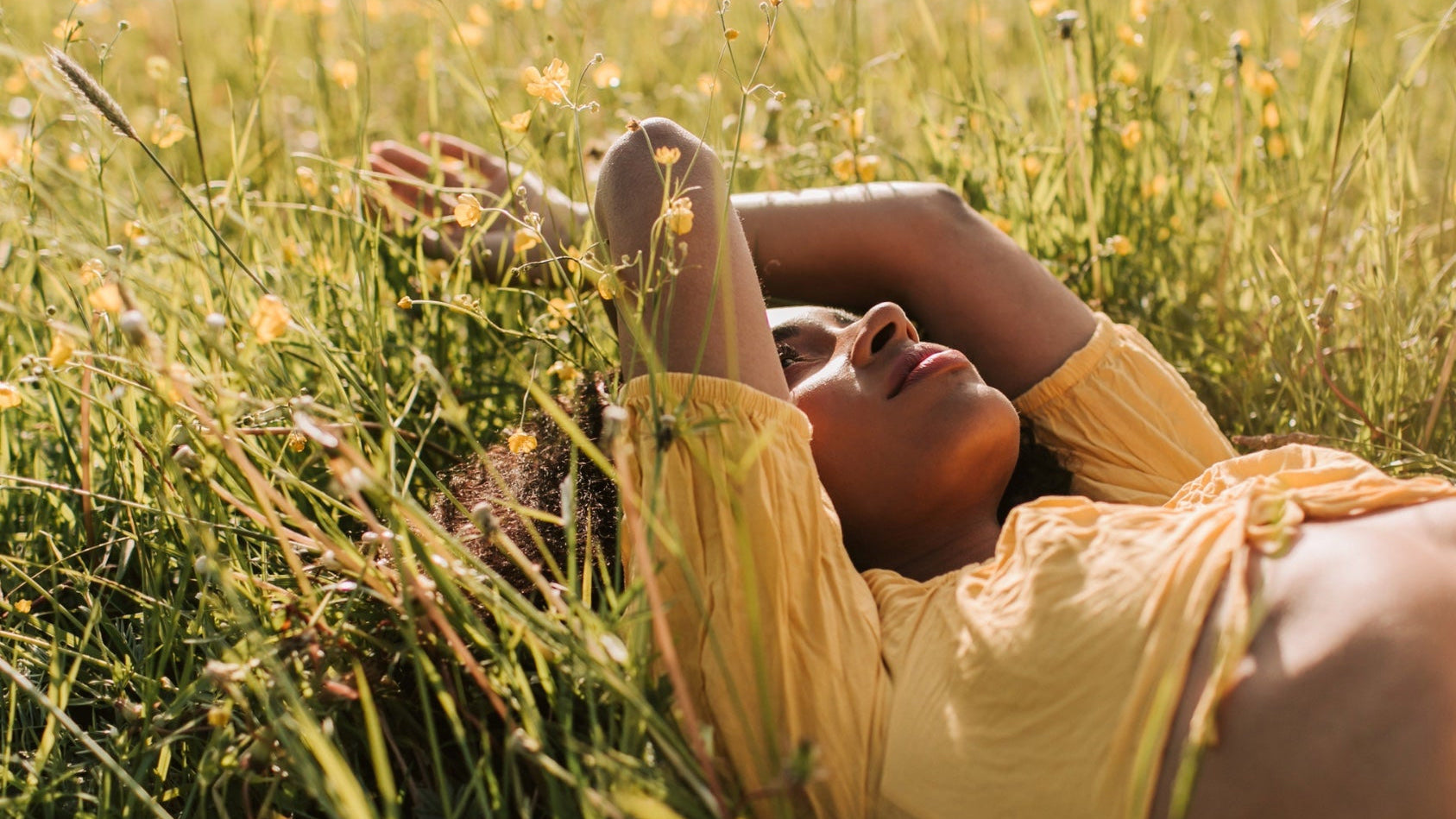 Natural Scottish skincare inspired by the landscape, featuring a woman relaxing in a summer meadow.